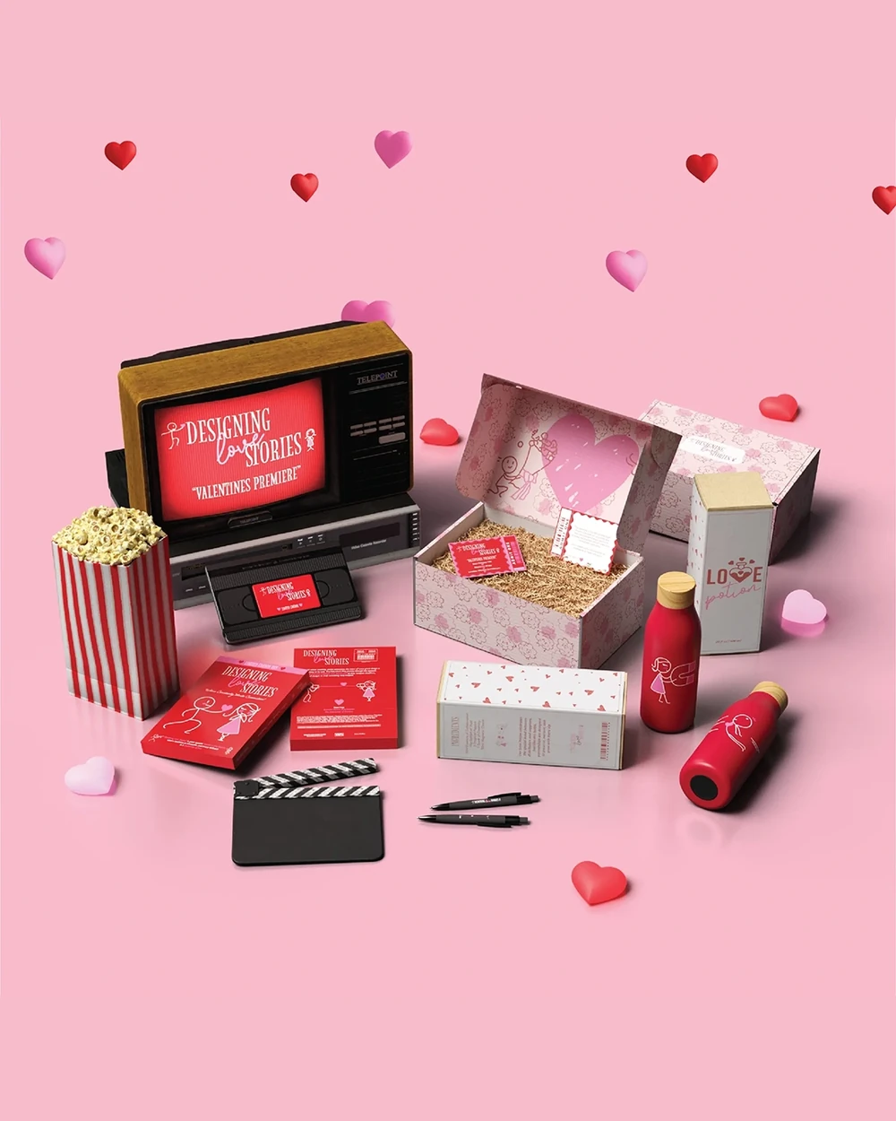 Valentine's Day gift kit with a small retro TV, popcorn box and red bottles on pink with hearts